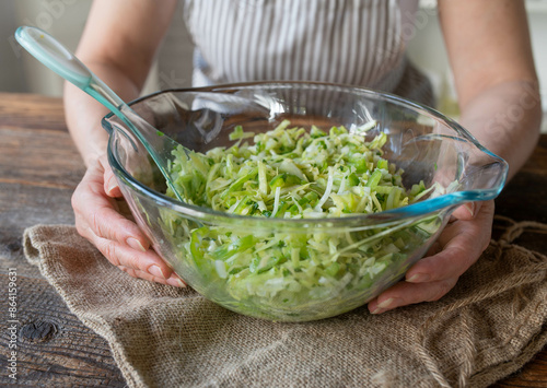 Homemade coleslaw salad with vinegar and oil, green peppers and celery in a glass bowl served by woman´s hands