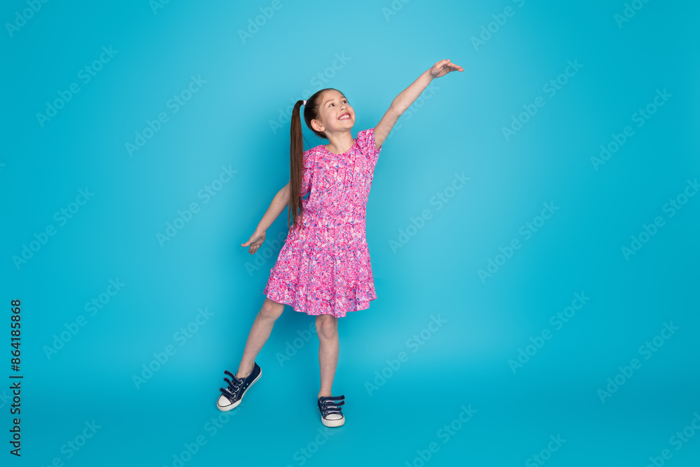 Full length photo of cheerful pretty little lady dressed pink clothes measure arm empty space isolated blue color background Full length photo of cheerful pretty little lady dressed pink clothes measure arm empty space isolated blue color background