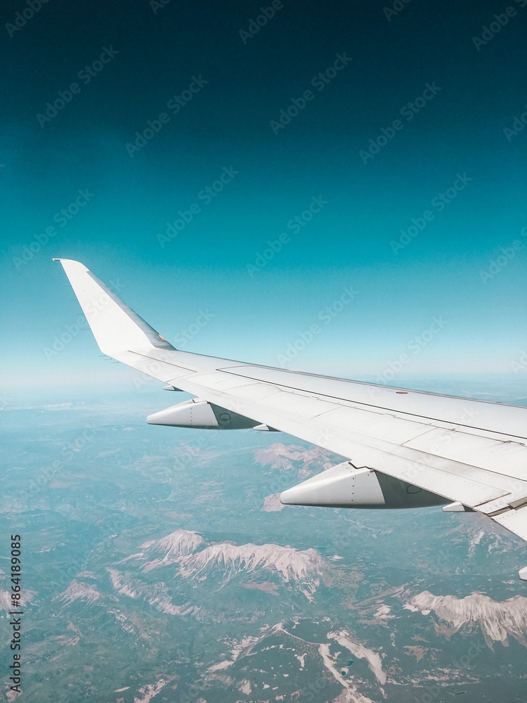 Obraz premium Wing on Airplane Flying over Mountains