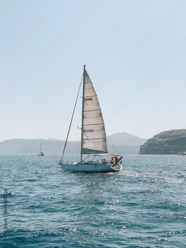 Naklejka premium Serene photograph of a boat gliding across the Aegean Sea near Santorini, Greece