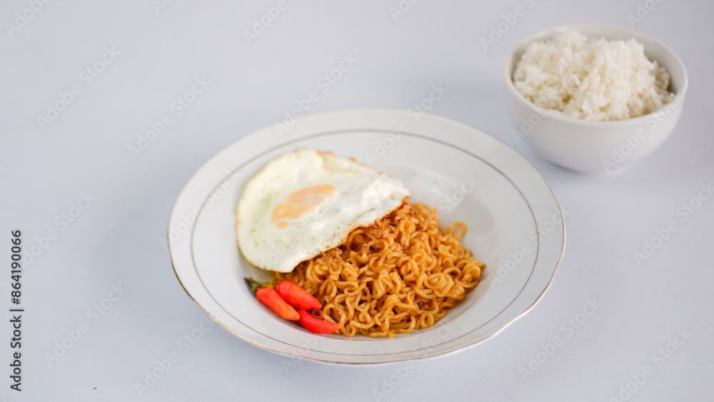 Fried noodles with fried egg and red cayenne pepper, served on a serving plate. Isolated on white background. Fried noodles with fried egg and red cayenne pepper, served on a serving plate. Isolated on white background.