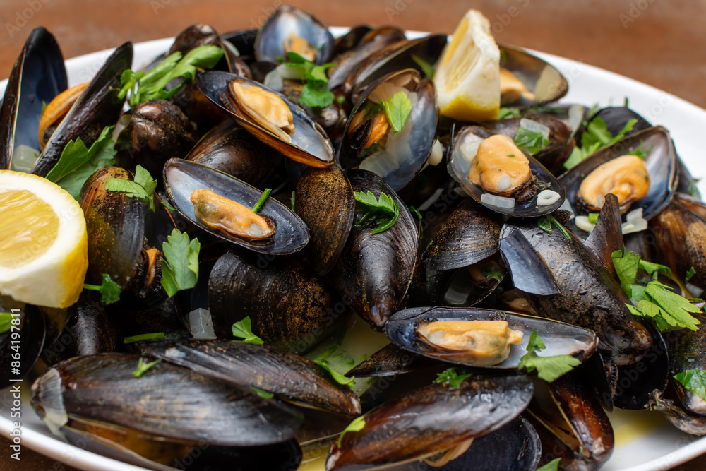 A white plate is covered with mussels and slices of lemon A white plate is covered with mussels and slices of lemon