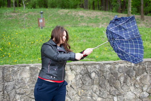 In the image, a woman is holding an umbrella that is being blown by the wind