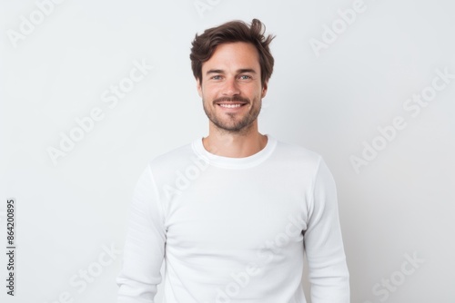 Portrait of a tender man in his 30s showing off a thermal merino wool top while standing against white background