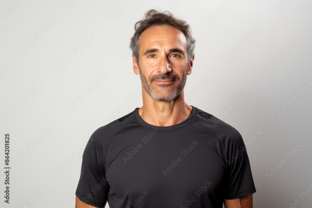 Portrait of a tender man in his 40s wearing a moisture-wicking running shirt while standing against white background Portrait of a tender man in his 40s wearing a moisture-wicking running shirt while standing against white background