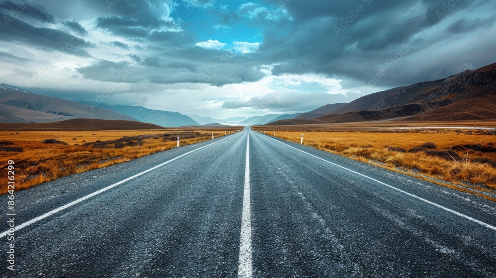 Fototapeta premium Scenic Long Road in Mountain Landscape Under Dramatic Sky Travel Inspiration, Adventure, and Nature Photography