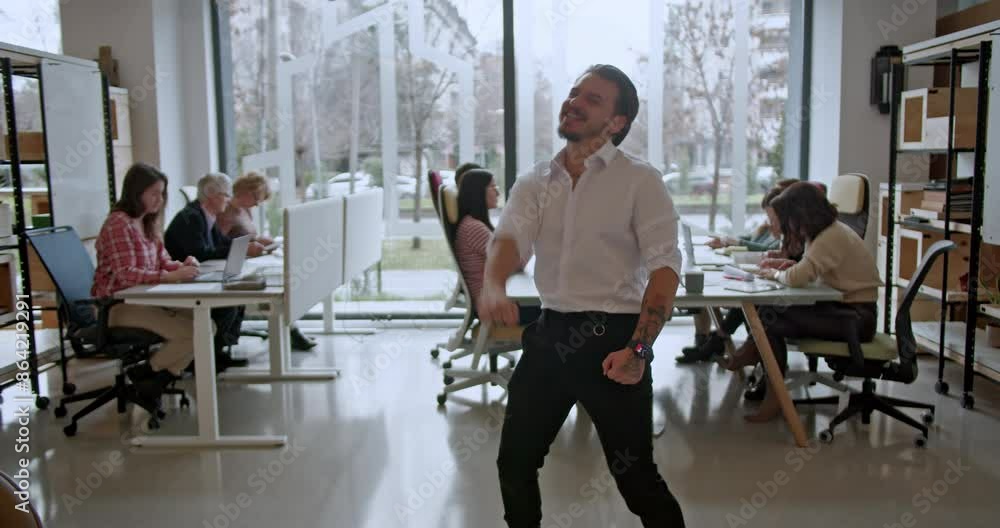 A man in a business office joyously celebrates a successful project, surrounded by coworkers focused on their tasks at their desks, showcasing teamwork and dedication. A man in a business office joyously celebrates a successful project, surrounded by coworkers focused on their tasks at their desks, showcasing teamwork and dedication.
