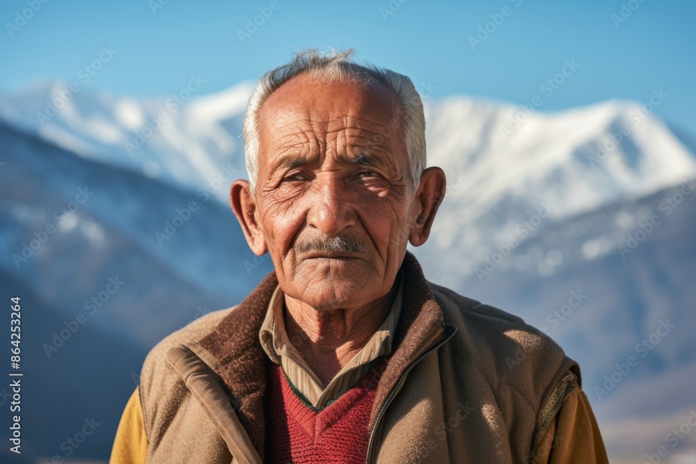 Portrait of a glad indian elderly man in his 90s wearing a sporty polo shirt isolated in snowy mountain range Portrait of a glad indian elderly man in his 90s wearing a sporty polo shirt isolated in snowy mountain range