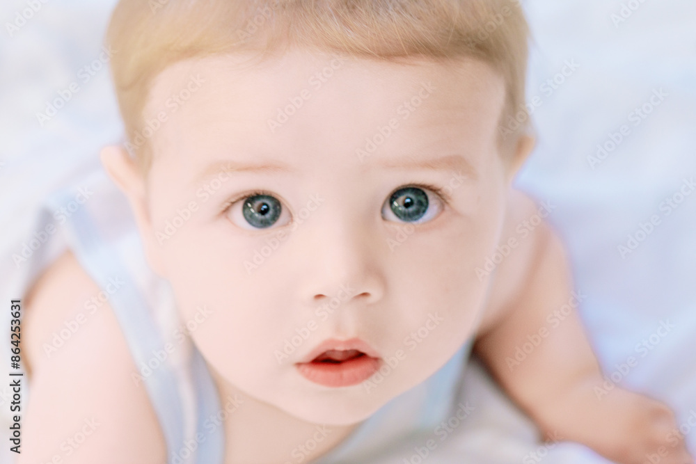 Adorable baby boy lying on stomach and looking with big blue eye Adorable baby boy lying on stomach and looking with big blue eye