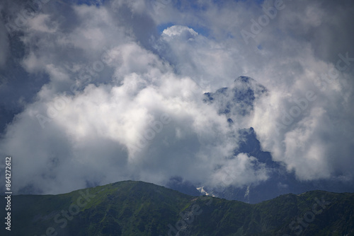  A mountaintop vista filled with abundant clouds in the sky, a plane in the foreground