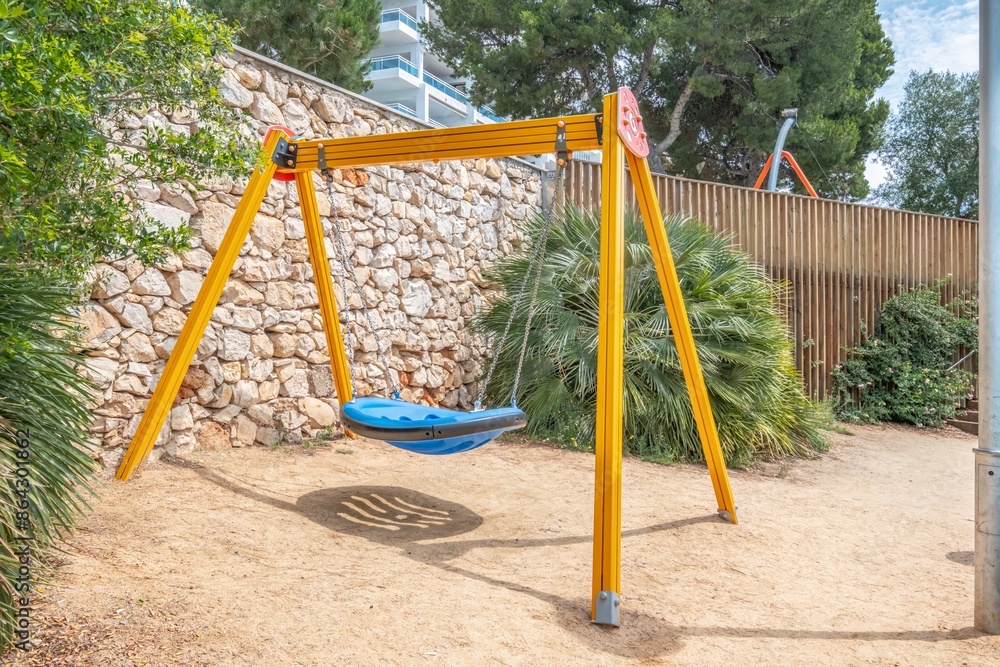 Fototapeta premium Colorful playground for children in public park. Colorful playground with slide, swings and other play equipment installed in a public park.