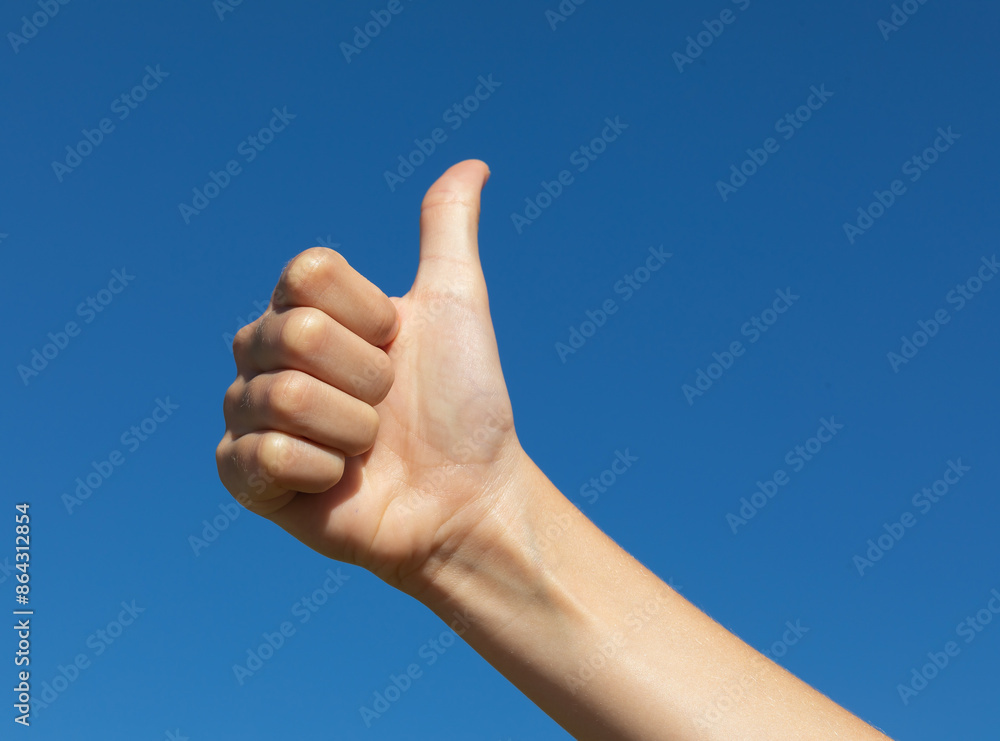 Teen girl showing thumbs up gesture against blue cloudless sky, concept on the theme everything is fine