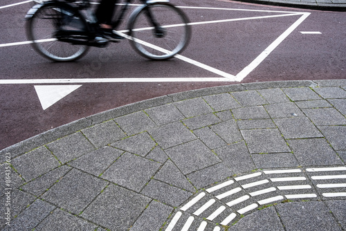 This image captures a cyclist in motion on a curved path with geometric patterns, representing the dynamic movement and rhythm of urban life and the blend of human activity with modern design. photo