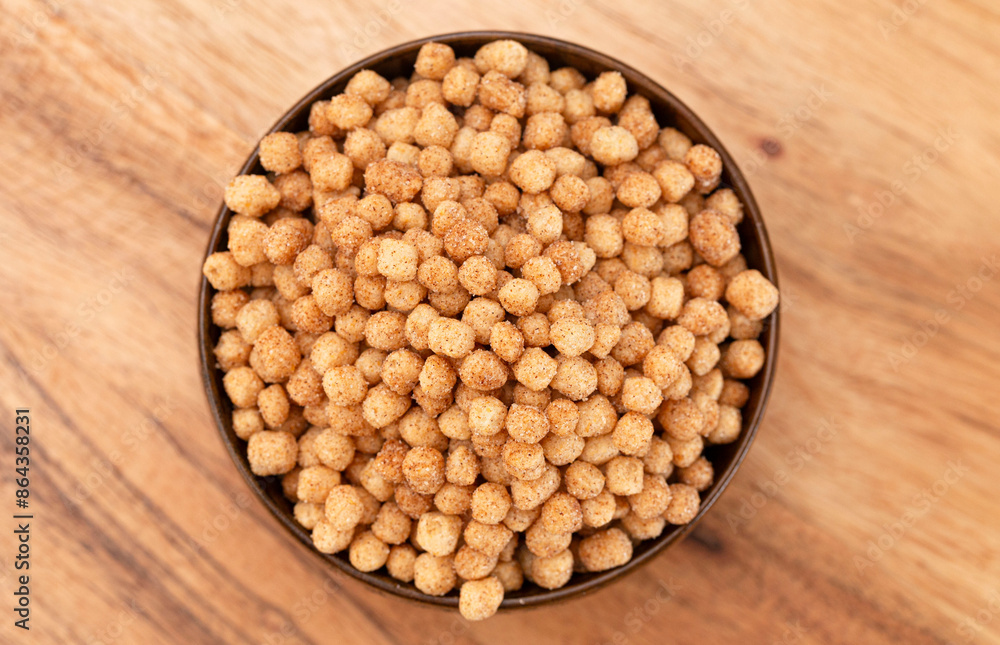 A Bowl of Small Ball Shaped Cinnamon Toast Flavored Breakfast Cereal on a Wooden Kitchen Table A Bowl of Small Ball Shaped Cinnamon Toast Flavored Breakfast Cereal on a Wooden Kitchen Table