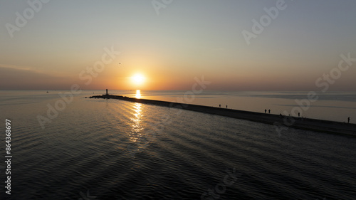 Bild auf Leinwand A sunset scene over a sizable water body features a pier anchored centrally
