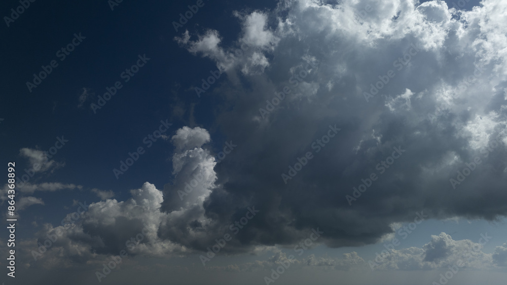 A plane flies against a backdrop of dense clouds in the sky, with a tranquil body of water visible in the foreground A plane flies against a backdrop of dense clouds in the sky, with a tranquil body of water visible in the foreground