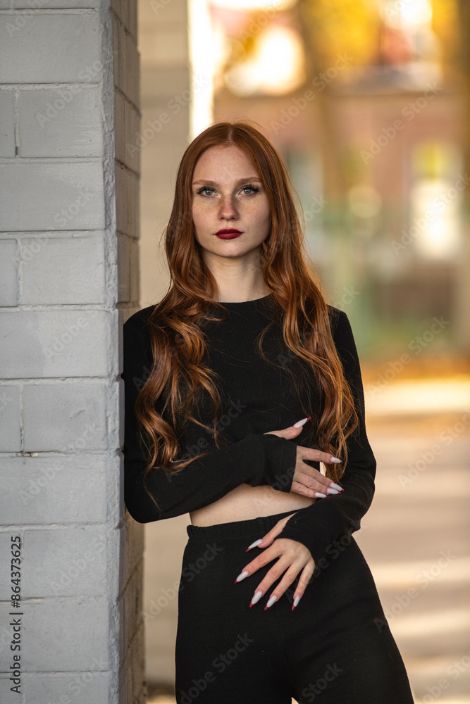 Portrait of a young beautiful red-haired girl in dark clothes outdoors. Portrait of a young beautiful red-haired girl in dark clothes outdoors.