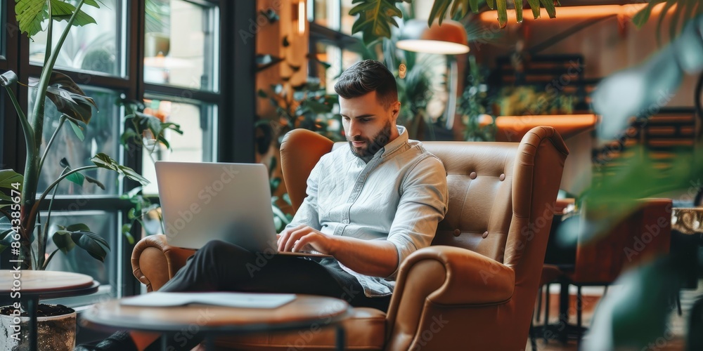 A man is sitting in a chair with a laptop on his lap A man is sitting in a chair with a laptop on his lap