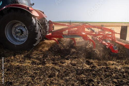 Tractor preparing land with seedbed cultivator.