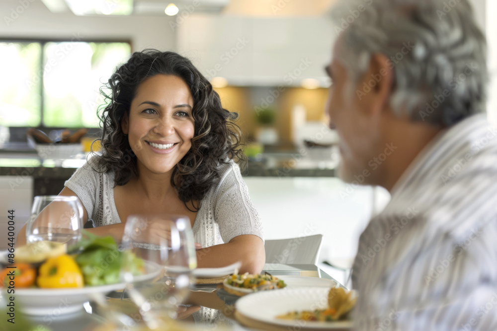Hispanic woman smiling at her partner while enjoying a meal at home Hispanic woman smiling at her partner while enjoying a meal at home