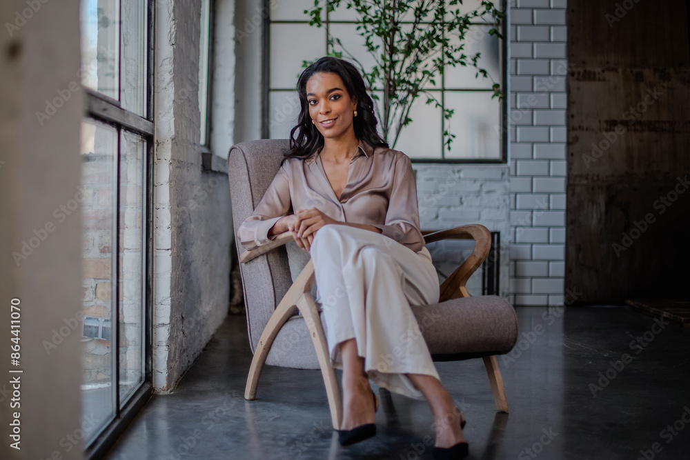 An attractive African American woman sitting in an armchair by the window An attractive African American woman sitting in an armchair by the window