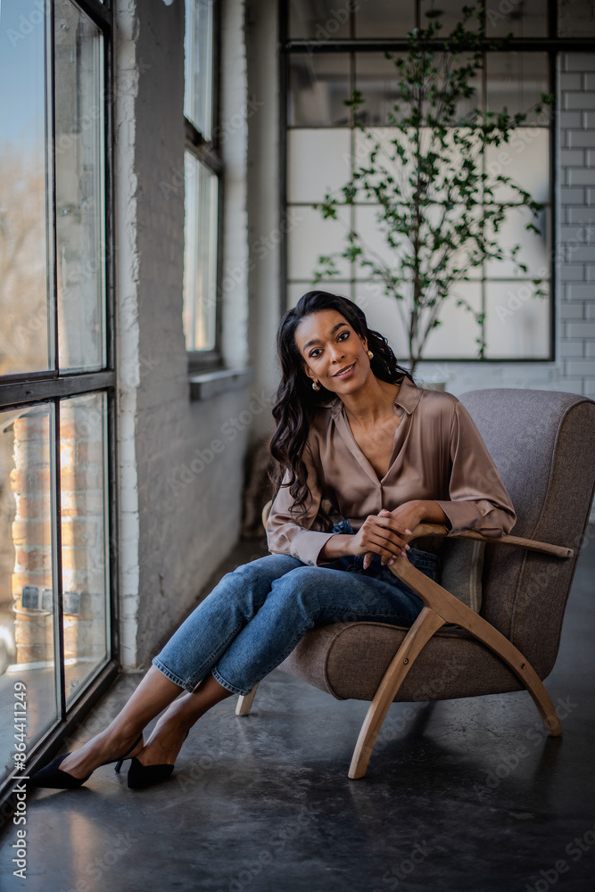 An attractive African American woman sitting in an armchair by the window An attractive African American woman sitting in an armchair by the window