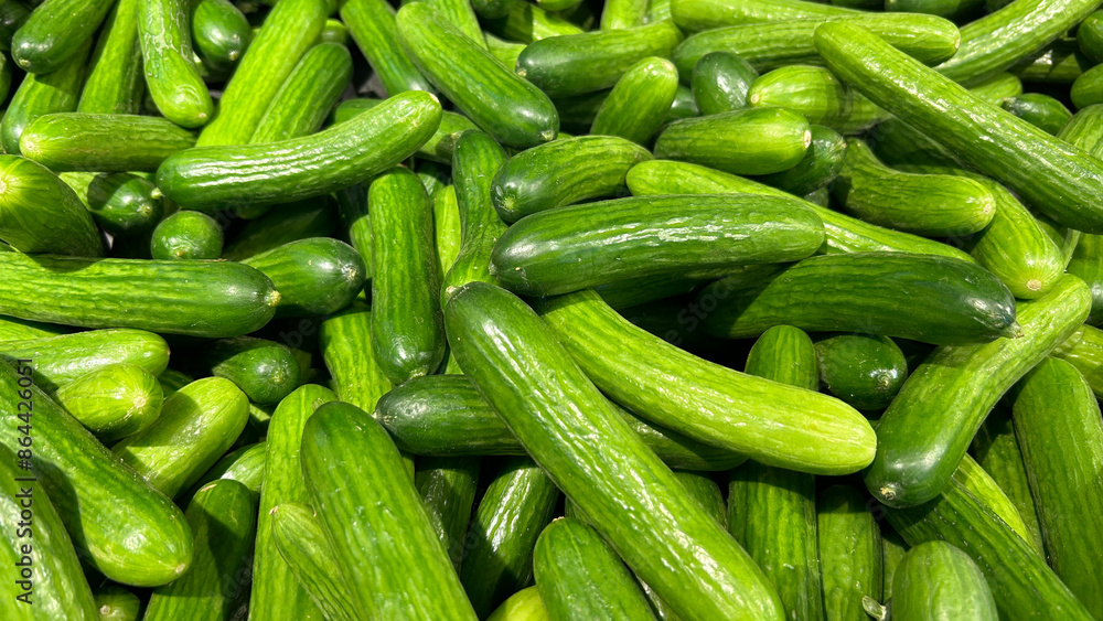 A pile of fresh green cucumbers is displayed at a market A pile of fresh green cucumbers is displayed at a market