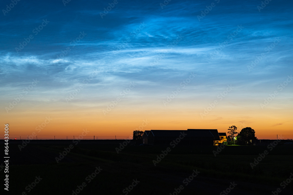 Fototapeta premium Scenic view of noctilucent clouds or NLC above a farm during the period of the shortest nights in June