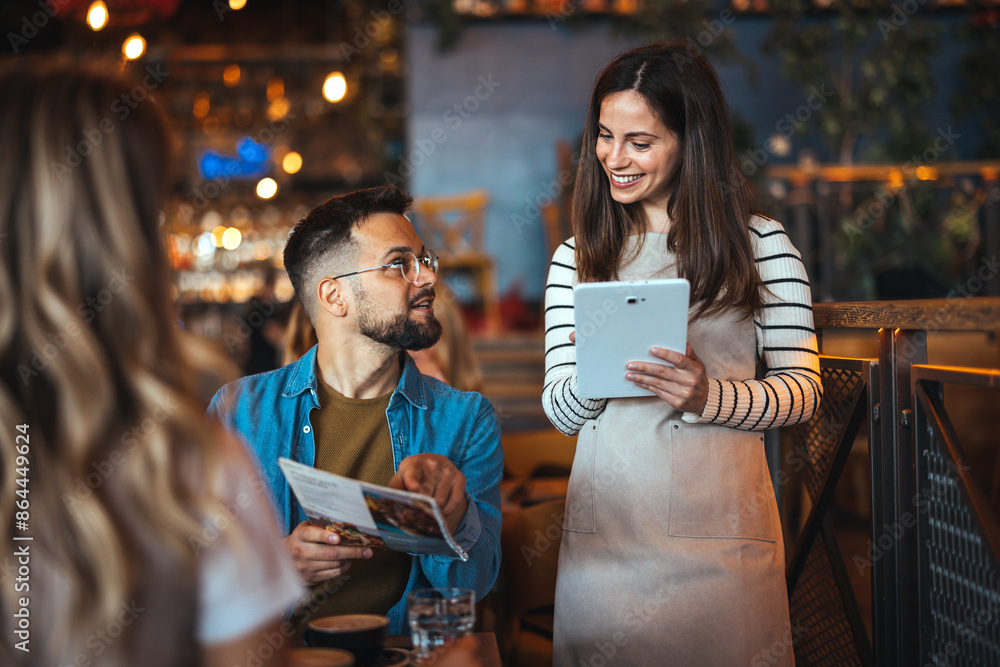 A happy female waitress wearing an apron interacts with dining guests, taking orders on a digital tablet in a cozy restaurant setting. A happy female waitress wearing an apron interacts with dining guests, taking orders on a digital tablet in a cozy restaurant setting.