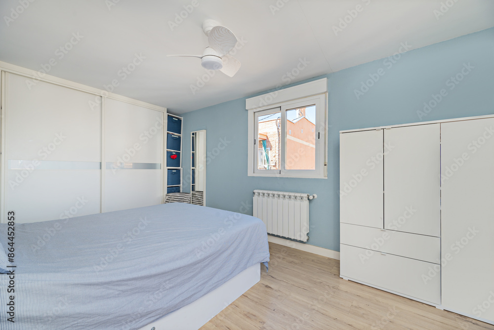 Bedroom with white furniture, desk with swivel chair, matching wardrobes, white aluminum and glass windows and blue painted walls Bedroom with white furniture, desk with swivel chair, matching wardrobes, white aluminum and glass windows and blue painted walls