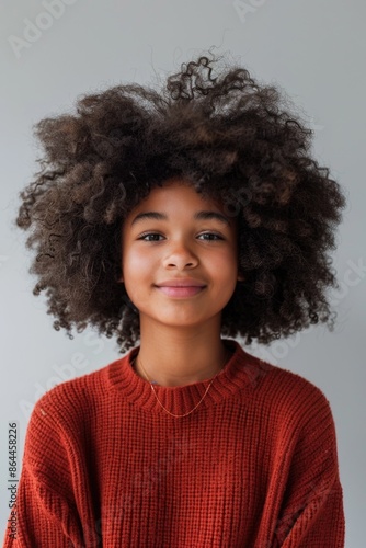 A young girl with an afro hairstyle smiles warmly at the camera