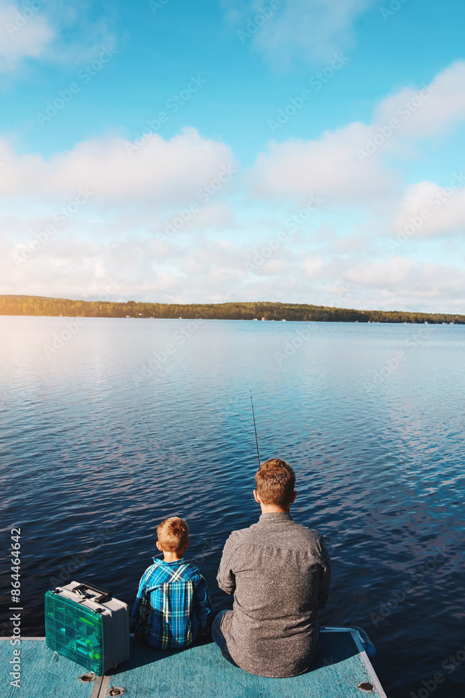 Fototapeta premium Fishing, together and back of man and son at lake in summer for vacation and relax in morning. Family, father and kid in nature by water for holiday, learning or gear for outdoor adventure with dad