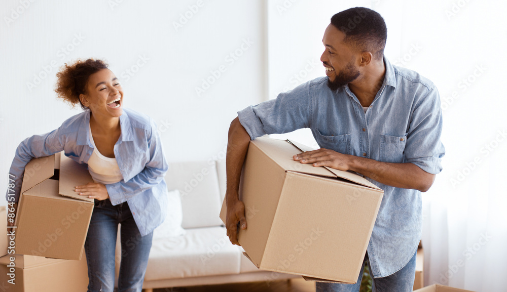 Joyful Afro Couple Carrying Moving Boxes Laughing Entering New Home. Happy Relocation Concept. Selective Focus Joyful Afro Couple Carrying Moving Boxes Laughing Entering New Home. Happy Relocation Concept. Selective Focus
