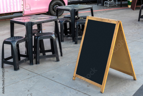 Obraz na płótnie Empty chalkboard next to tables and chairs and a food truck in a square in Brazil w salonie
