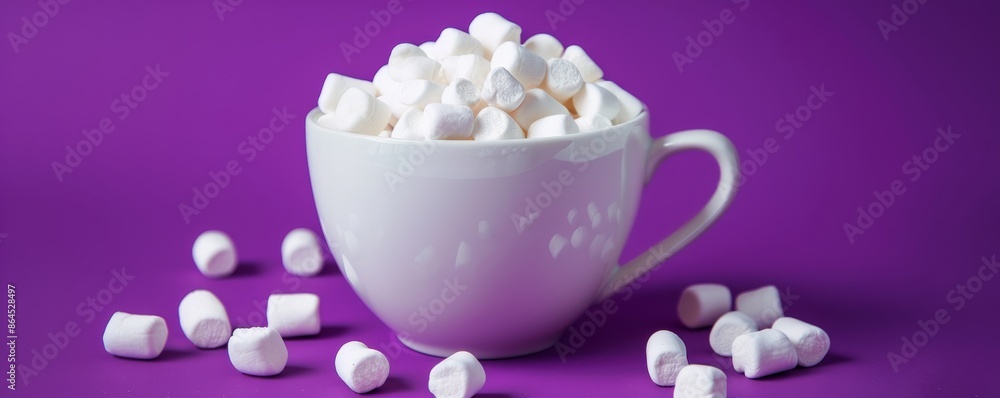 White teacup filled with mini marshmallows on purple background, food and dessert concept White teacup filled with mini marshmallows on purple background, food and dessert concept