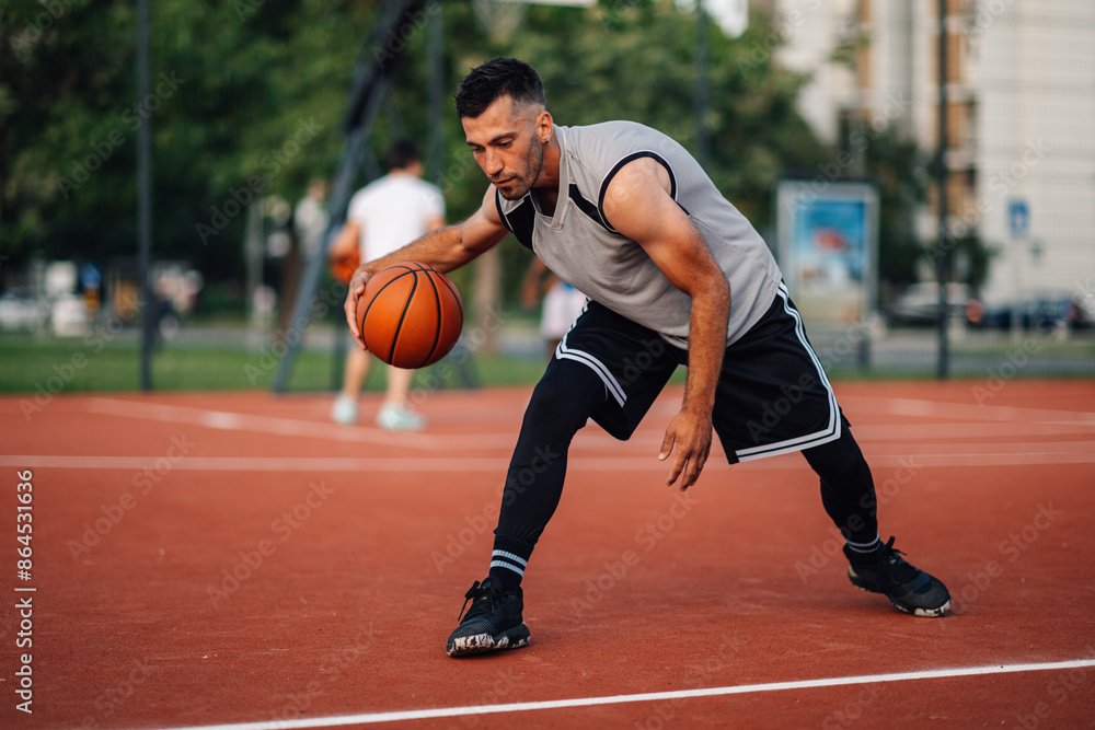 Man in motion playing basketball n an outdoor court Man in motion playing basketball n an outdoor court