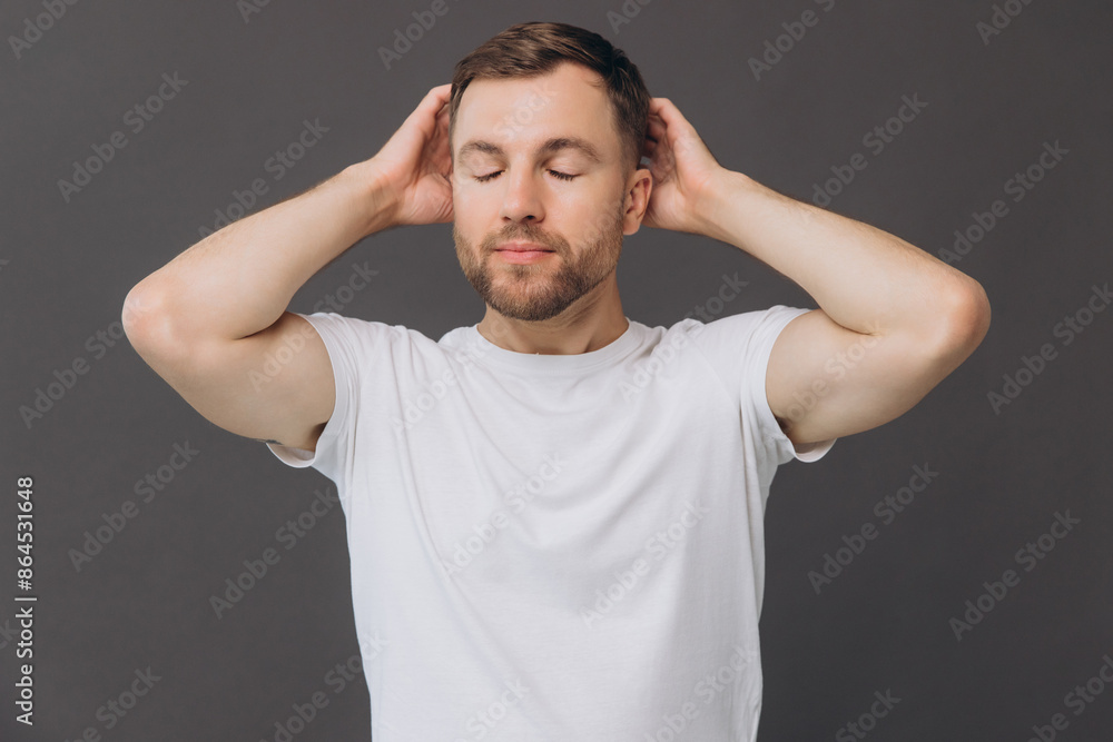 Cute bearded man massaging his scalp on gray background in studio, beauty and care concept Cute bearded man massaging his scalp on gray background in studio, beauty and care concept