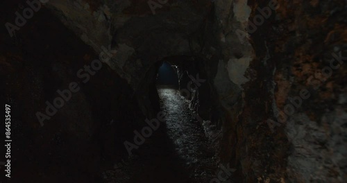 Walking inside a dark and tight tunnel with a light at the end in a first person view FPV photo