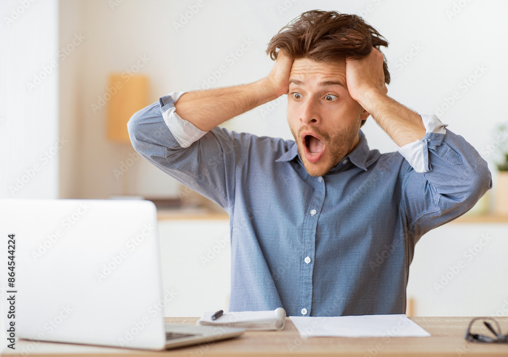 Oh no. Frustrated man looking at laptop holding hands on head at home. Copy space Oh no. Frustrated man looking at laptop holding hands on head at home. Copy space