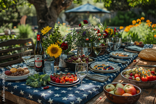 Outdoor summer dinner party with vegetables and fruit, blue and white decor, flowers, and a farmhouse table setting with an American flag backdrop and blue and white tablecloth with USA flag pattern.