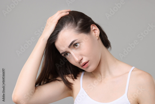 Sad woman with hair loss problem on grey background