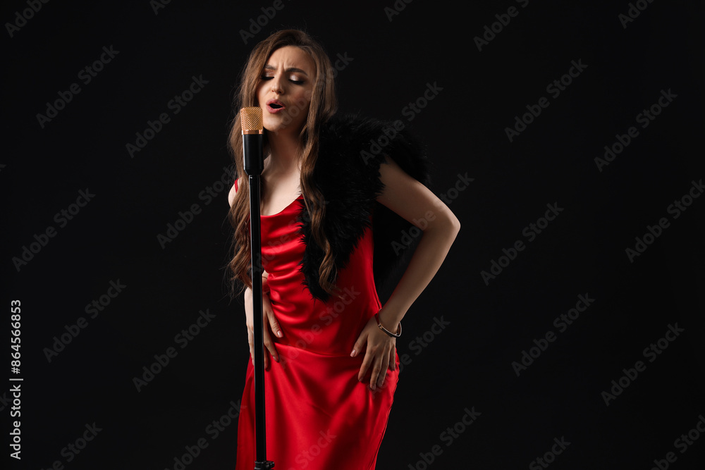 Beautiful young woman in stylish dress with microphone singing on black background Beautiful young woman in stylish dress with microphone singing on black background
