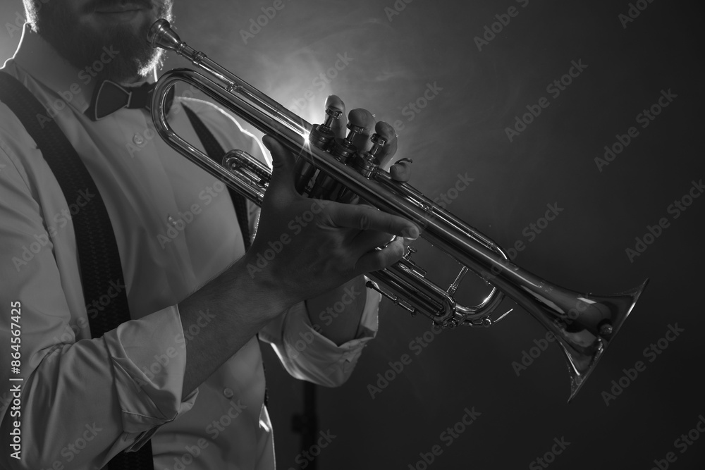 Obraz premium Professional musician holding trumpet on dark background, closeup with space for text. Black and white effect