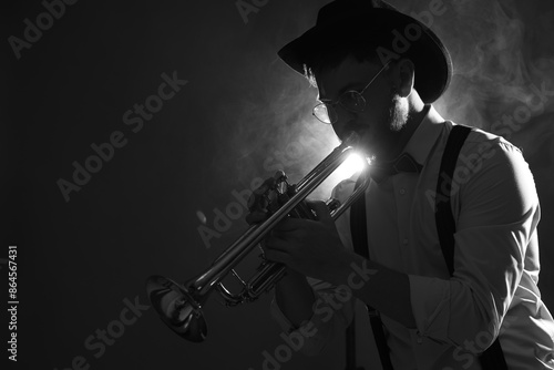 Canvas Print Professional musician playing trumpet on dark background with smoke, space for text