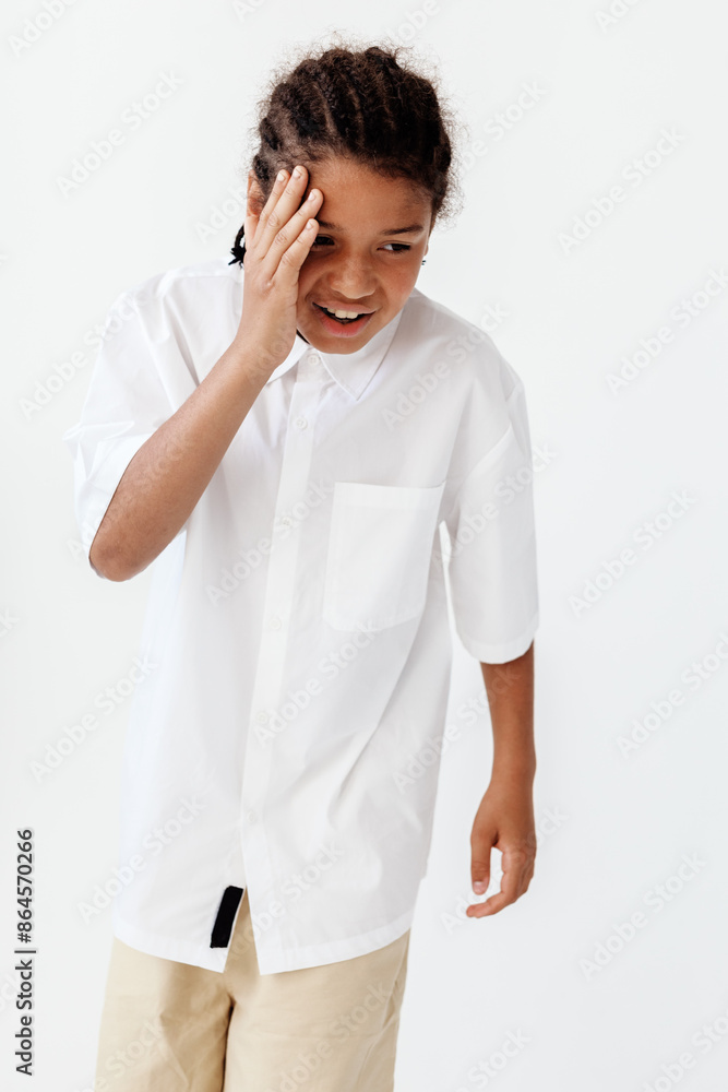 Upset young boy in stylish outfit covering face with hands in a candid moment Upset young boy in stylish outfit covering face with hands in a candid moment