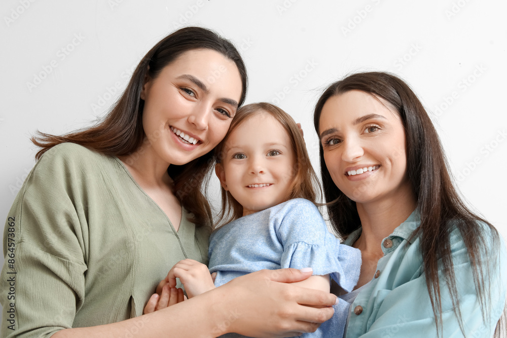 Young lesbian couple with adopted little girl on light background, closeup Young lesbian couple with adopted little girl on light background, closeup