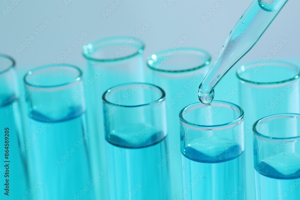 Dripping liquid from pipette into test tube on blurred background, closeup. Laboratory analysis Dripping liquid from pipette into test tube on blurred background, closeup. Laboratory analysis