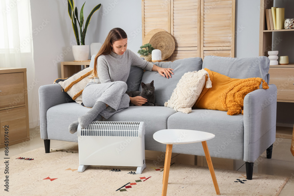 Young woman with cute cat and radiator at home Young woman with cute cat and radiator at home