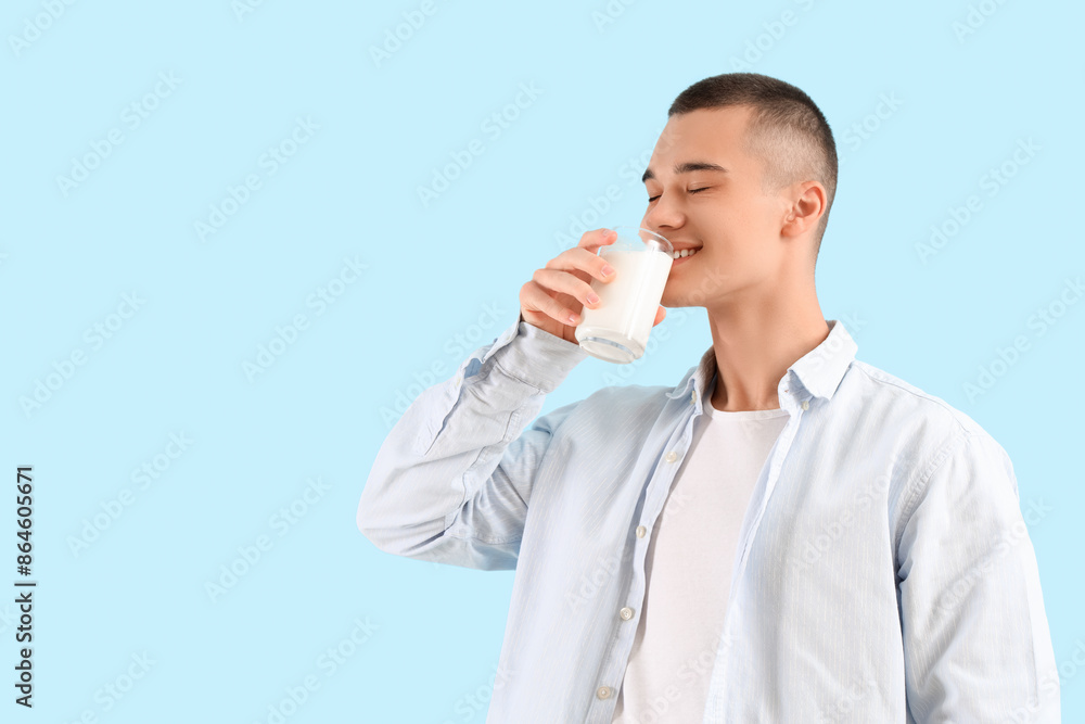 Teenage boy drinking milk on blue background Teenage boy drinking milk on blue background
