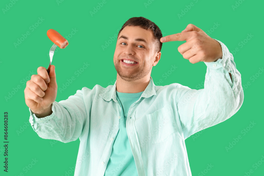 Young man pointing at tasty sausage on green background Young man pointing at tasty sausage on green background